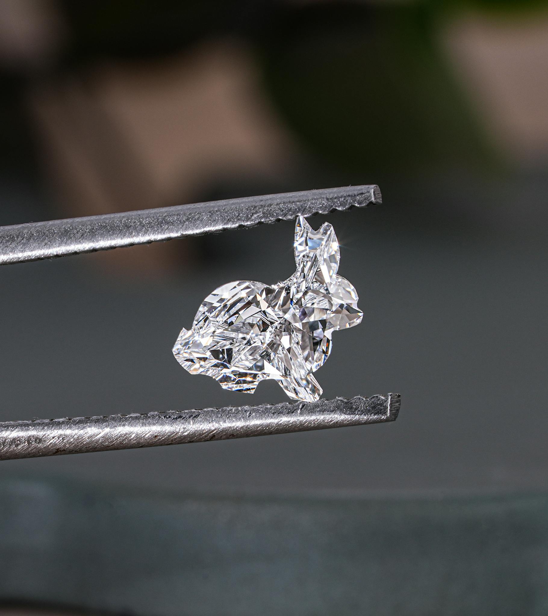 Close-up of a sparkling rabbit-shaped lab-grown diamond held by tweezers in Surat.